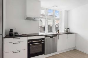 a kitchen with white cabinets and a sink and a window at Premium High-Street Home w Large Private Terrace in Aarhus