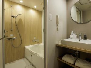a bathroom with a shower and a sink and a mirror at Hotel Nikko Narita in Narita