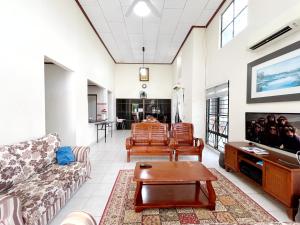 un soggiorno con un divano e una TV di A'FAMOSA Pool Villa by S&T Homez ad Alor Gajah