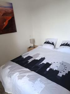 Un dormitorio con una cama blanca con un cuadro en la pared. en Dans la brise du Rhône, en Arles