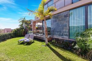 a house with two chairs and a palm tree at Holiday Home Villa Gema in Maspalomas