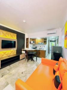 a living room with an orange couch and a table at Suite Hotel Apartment Legian by RCP in Seminyak +4 photos