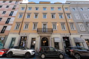 a large building with cars parked in front of it at Maria Cristina Boutique Rooms in Trieste
