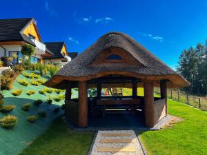 a gazebo with a thatched roof in a yard at Słoneczne Chatki in Knurów