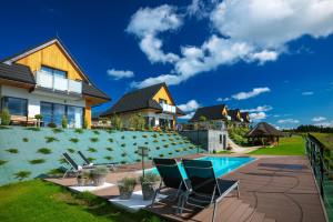 a house with a swimming pool and chairs in the yard at Słoneczne Chatki in Knurów