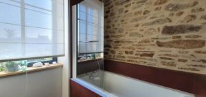 a bathroom with a bath tub next to a stone wall at Les Grands Gîtes de Cancale, gîtes de charme avec jacuzzi in La Coudre +37 photos