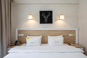 a bedroom with a bed with white sheets and white pillows at Helios Hotel & SPA in Bukovel