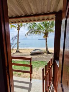 a view of a beach with palm trees and the ocean at Suítes Sol e Mar - Ilha Grande in Angra dos Reis