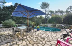 a patio with a table and an umbrella next to a pool at Cozy Home In Besse-Sur-Issole in Besse-sur-Issole