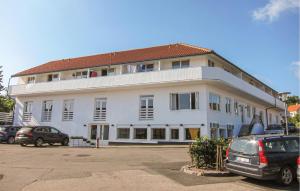 a white building with cars parked in a parking lot at Stunning Apartment In Gudhjem in Gudhjem