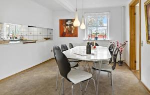 a kitchen and dining room with a white table and chairs at 5 Bedroom Lovely Home In Aakirkeby in Åkirkeby