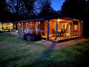 a log cabin with a deck and a grill at Drentse Sleutels 6 persoons huisje met jacuzzi in Erm