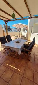 a table with chairs and an umbrella on a patio at Apartment happy place mit Meerblick in Alcalá