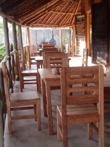 a group of wooden chairs and tables in a restaurant at SHADRACK BackPackers in Nungwi +32 photos