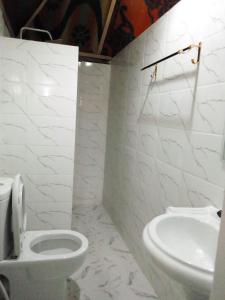 a white bathroom with a toilet and a sink at SHADRACK BackPackers in Nungwi