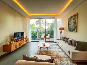 a living room with a couch and a tv at Villa Suarga Des Anicca in Ubud
