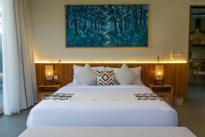 a bedroom with two beds and a painting on the wall at Villa Suarga Des Anicca in Ubud