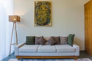 a couch in a living room with a painting on the wall at Villa Suarga Des Anicca in Ubud