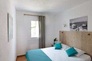 a bedroom with a bed with blue pillows and a window at Domaine Bocca di Feno in Bonifacio +70 photos