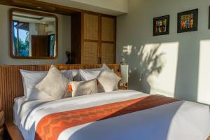 a bedroom with a large bed with an orange and white blanket at Villa Suarga Des Anicca in Ubud