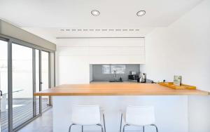 テルアビブにあるLuxury Beachfront Penthouse at Haari By HolyGuestの白い壁のキッチン、木製カウンター(白い椅子付)