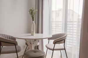a white table with chairs and a vase with flowers at Urban Nest in Szczecinek