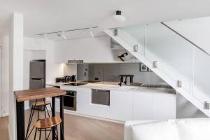a kitchen with white cabinets and a wooden table at KozyGuru Sydney CBD Harbor View Loft with Parking in Sydney