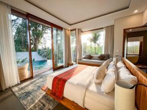 a bedroom with a large bed and large windows at Villa Suarga Des Anicca in Ubud