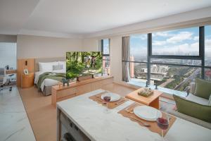 salon z łóżkiem i dużym oknem w obiekcie Somerset Fengdong Xi'an w mieście Xianyang