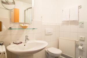 a white bathroom with a sink and a toilet at Hotel Pfeffermühle in Siegen