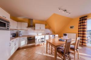 a kitchen with white cabinets and a wooden table at Ferienwohnung Storchenhorst - gemütliches Apartment mit Kamin in Göhren-Lebbin +10 photos