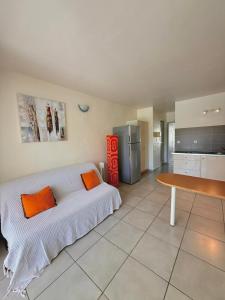 a bedroom with a bed with orange pillows and a table at COLIBRI DAMPIERRE Appartement cosy au Gosier avec piscine, terrasse et vue mer in Le Gosier