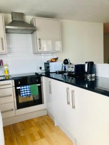 a kitchen with white cabinets and black counter tops at 20 minute to central London beautiful apartment in London