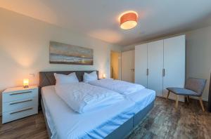 a bedroom with a large bed and a chair at Hafenflair- Apartment mit Balkon & Kamin in der Hafenresidenz in Waren