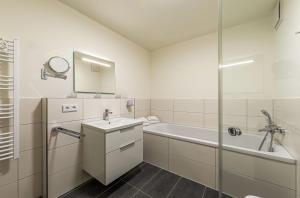 a bathroom with a tub and a sink and a shower at Hafenflair- Apartment mit Balkon & Kamin in der Hafenresidenz in Waren +15 photos