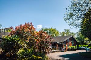 a building with trees and bushes in front of it at Limetree Lodge 2 at Thurston Manor Leisure Park in Dunbar