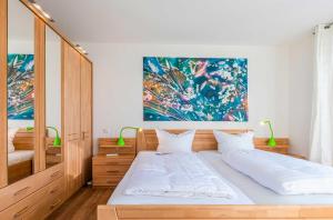 ein Schlafzimmer mit einem Bett und einem Gemälde an der Wand in der Unterkunft Hafenperle - Apartment mit Balkon & Wellnessbereich in der Hafenresidenz in Waren (Müritz)