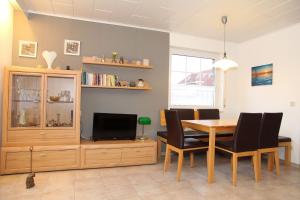 a dining room with a table and a tv at Seerobbe in Norddeich