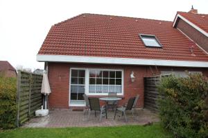 a patio with a table and chairs in front of a house at Seerobbe in Norddeich