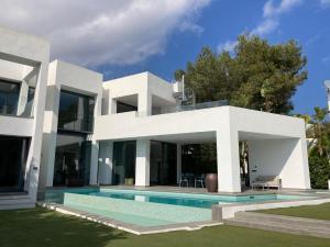 a white house with a swimming pool in front of it at Villa Lux Mar in Cala Llena