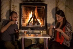 un uomo e una donna che bevono il tè davanti al camino di Divaisib Termal Resort Hotel & Spa a Kozaklı