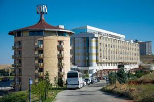 un autobus parcheggiato di fronte a un edificio con una torre di Divaisib Termal Resort Hotel & Spa a Kozaklı