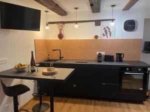a kitchen with a black counter and a sink at Au Refuge des amoureux avec baignoire Balnéo 2 personnes in Sélestat