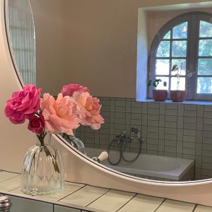 a bathroom with a vase with flowers in front of a mirror at Château Doré les Tours - Appartement Loup in Montfaucon +43 photos