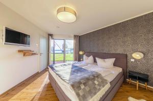 a bedroom with a large bed and a television at Am Lütten Meer - Apartment in der Hafenresidenz mit Terrasse & Müritzblick in Waren