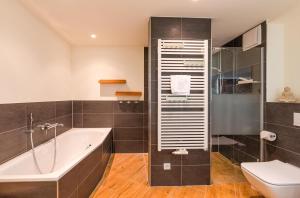 a bathroom with a bath tub and a toilet at Am Lütten Meer - Apartment in der Hafenresidenz mit Terrasse & Müritzblick in Waren +19 photos