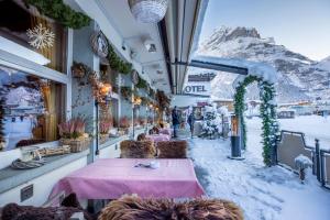 a restaurant with snow covered tables and a mountain at Hotel Kreuz & Post Grindelwald in Grindelwald