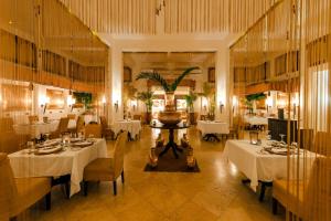 un restaurante con mesas y sillas blancas en una habitación en Baraza Resort and Spa Zanzibar, en Bwejuu