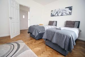 Dos camas en una habitación con suelo de madera. en The Lockett Wonderful Large Bungalow Plympton, Plymouth Free Parking By StayStaycations, en Plymouth