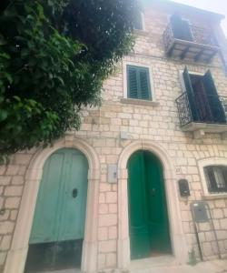 a building with two green doors and a balcony at Vannelli Rooms in Castelbottaccio